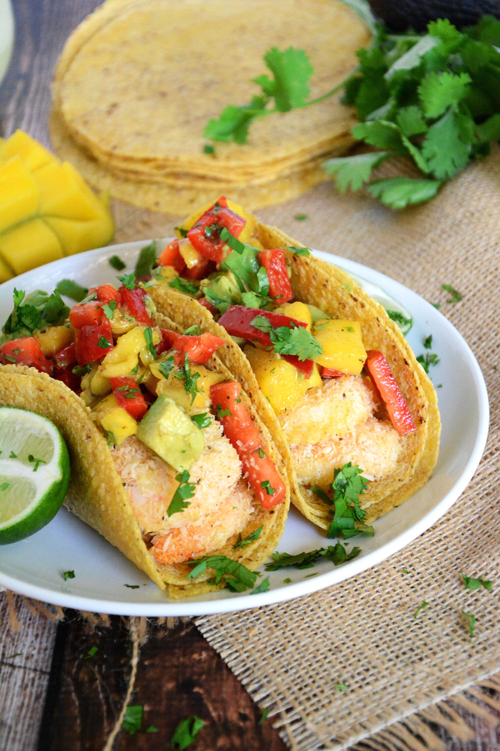 Healthy and Quick Shrimp Tacos sweetened with coconut and topped with a sweet and spicy salsa of mango, red pepper and avocado! 