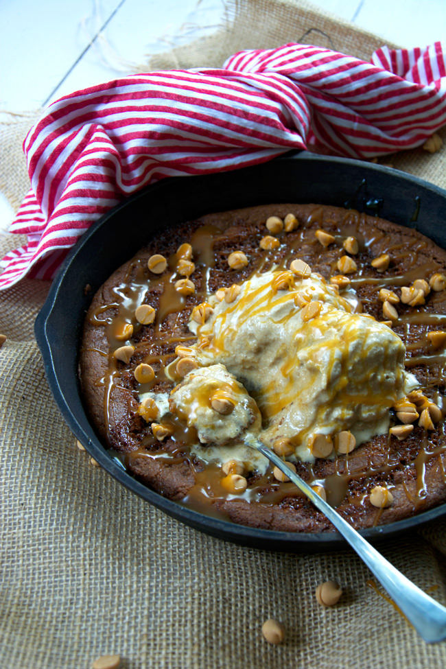 A flourless peanut butter cookie, filled with caramel and topped with caramel ice cream is an incredible skillet dessert that is ready in under 30 minutes! #peanutbuttercookie #glutenfree #dessert