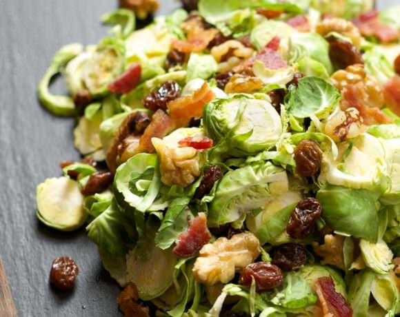 Delicately shaved brussels sprout salad tossed in a simple maple dijon vinaigrette, complete with crisp bacon and sweet raisins!