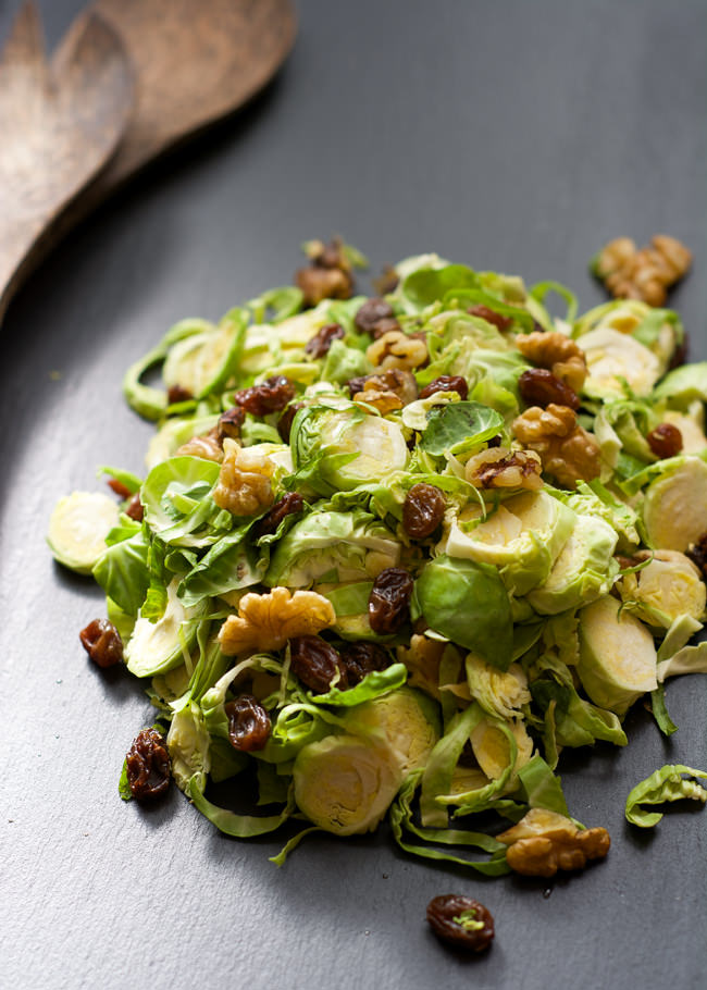 Delicately shaved brussels sprout salad tossed in a simple maple dijon vinaigrette, complete with crisp bacon and sweet raisins! 