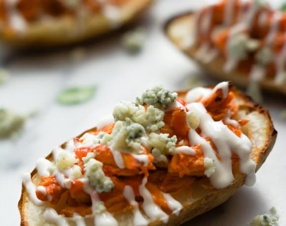 Buffalo Chicken Stuffed Potato Skins with Honey Blue Cheese Sauce are the perfect party food! Spicy shredded chicken loaded onto a crispy potato skin and drizzled with a homemade blue cheese sauce! #potatoskins #buffalo #appetizer #glutenfree