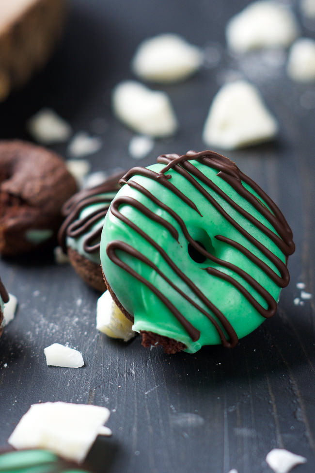 Your favorite Girl Scout Cookie just took over breakfast in these Mini Thin Mint Donuts! Tender chocolate donuts covered with mint white chocolate icing and a chocolate drizzle!