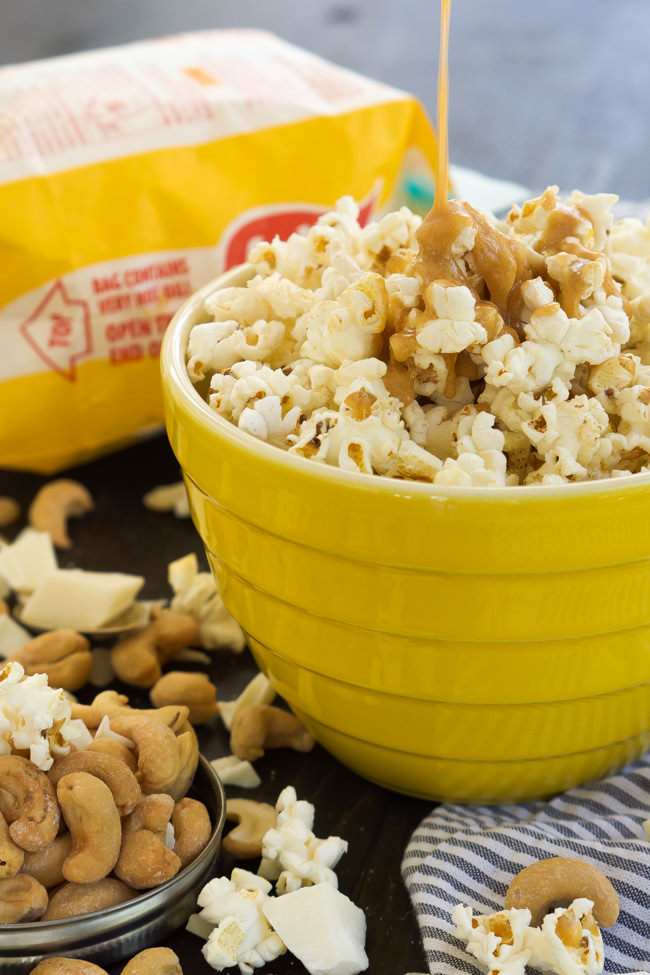 A sweet and salty treat that takes minutes to make! Skinny Peanut Butter Caramel Popcorn is made with only natural ingredients and is tossed with cashews and white chocolate for a sweet treat!