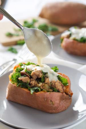 Kale and Sausage Stuffed Sweet Potatoes are an easy dinner idea, filled with sweet sausage and smothered in an easy white cheese sauce!
