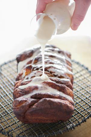 Lightened Up Cinnamon Roll Pull Apart Bread as the ooey gooey flavor of your favorite sweet rolls, but in an easy and fun loaf form! Flakey biscuits layered with a lightened up cinnamon sugar mixture and drizzled in a delicious glaze! The perfect treat for any morning!