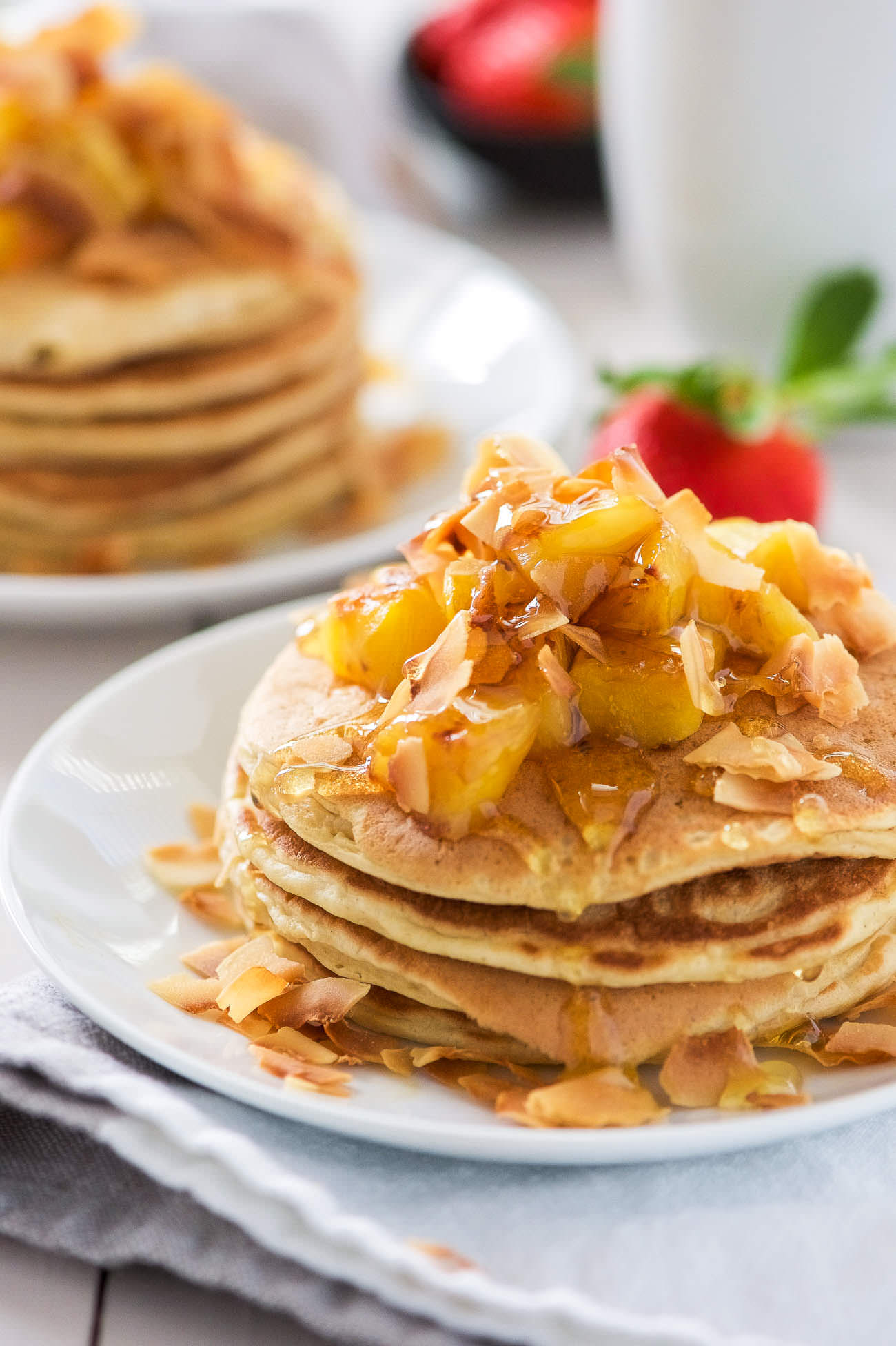 These Honey Pineapple and Toasted Coconut Pancakes are light, fluffy and filled with tropical flavors! These pancakes are the perfect start to a weekend breakfast or brunch!
