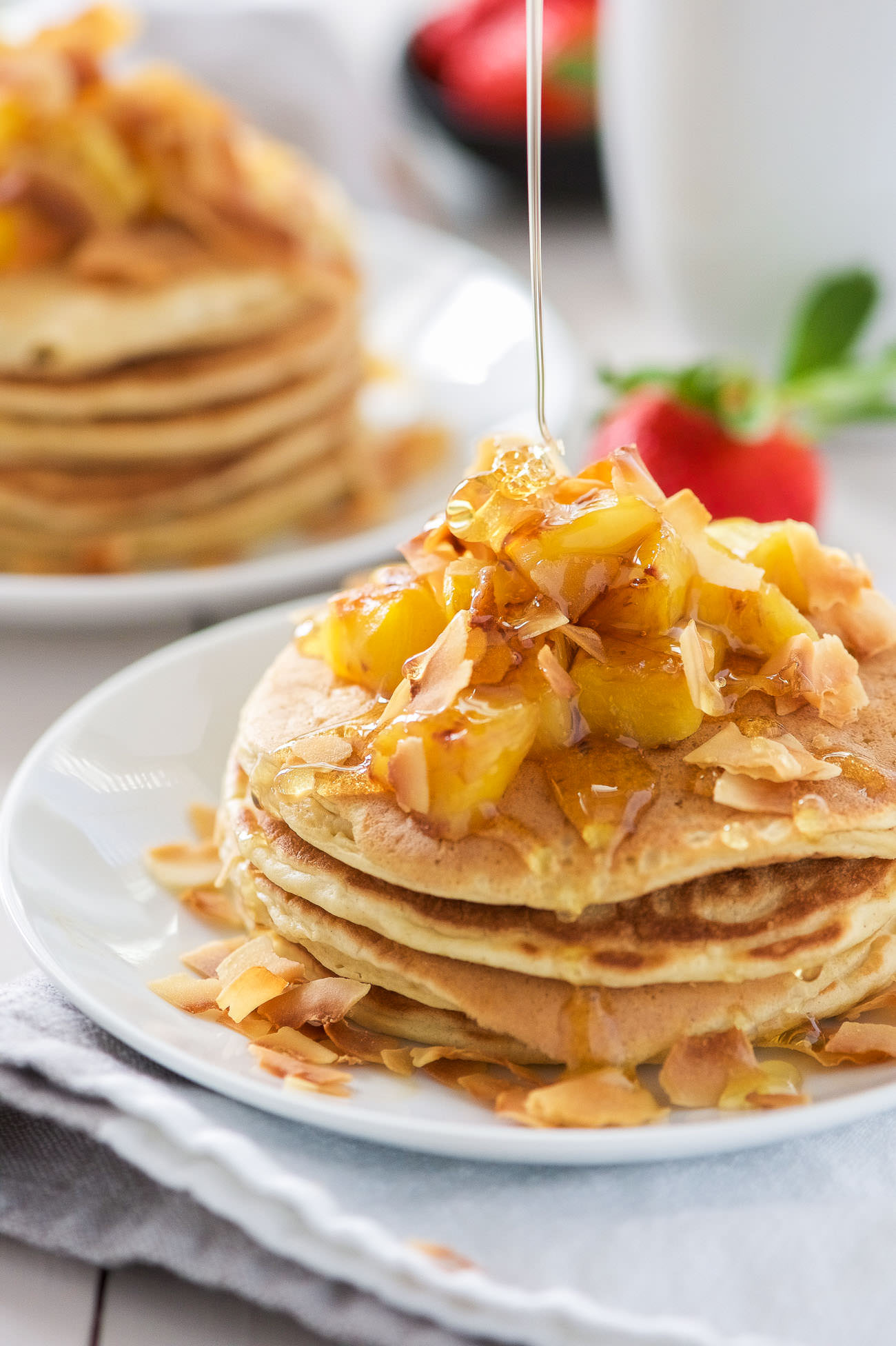 These Honey Pineapple and Toasted Coconut Pancakes are light, fluffy and filled with tropical flavors! These pancakes are the perfect start to a weekend breakfast or brunch!