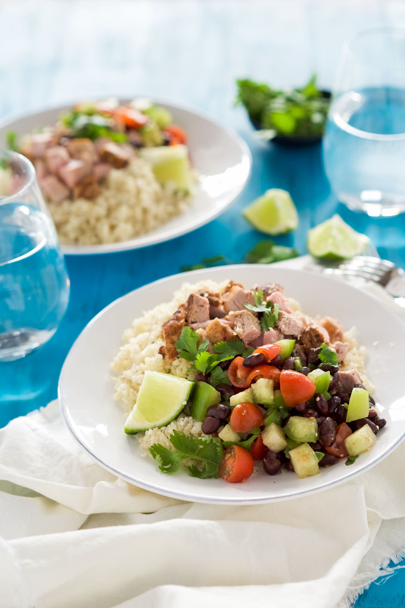 Chipotle Pork Carnita Burrito Bowls with Cumin Lime Rice are a healthy, homemade tex mex favorite! Filled with juicy, spiced pork, a homemade black bean salsa and lightened up cumin lime cauliflower rice!