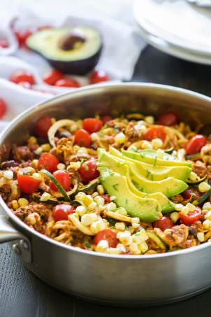One Pot Cheesy Taco Zucchini Noodle Skillet is a healthy spin on Taco Tuesday! Zucchini noodles, enchilada spiced ground turkey, black beans, corn and creamy avocado help makeover this dish!