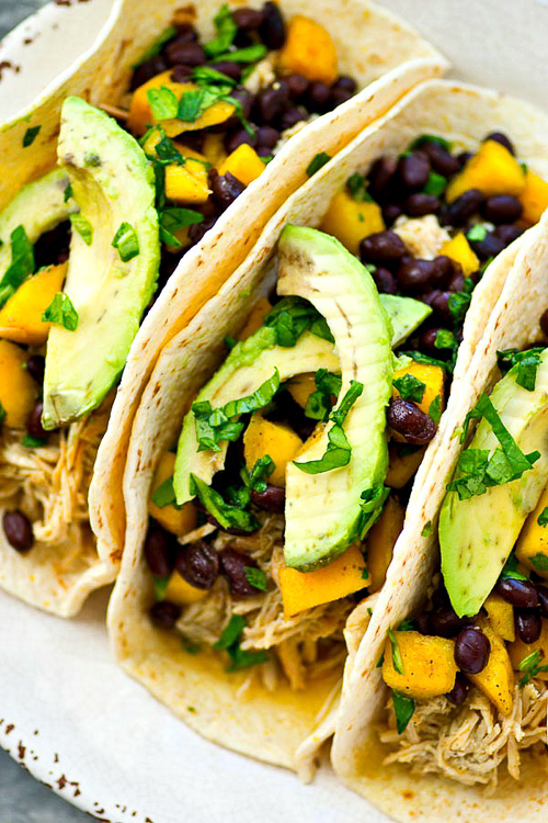 Up your taco night game with these INSANELY-easy crockpot green chile chicken tacos! The chicken is unbelievably tender and a mango black bean salsa piled on top brings tons of flavor!